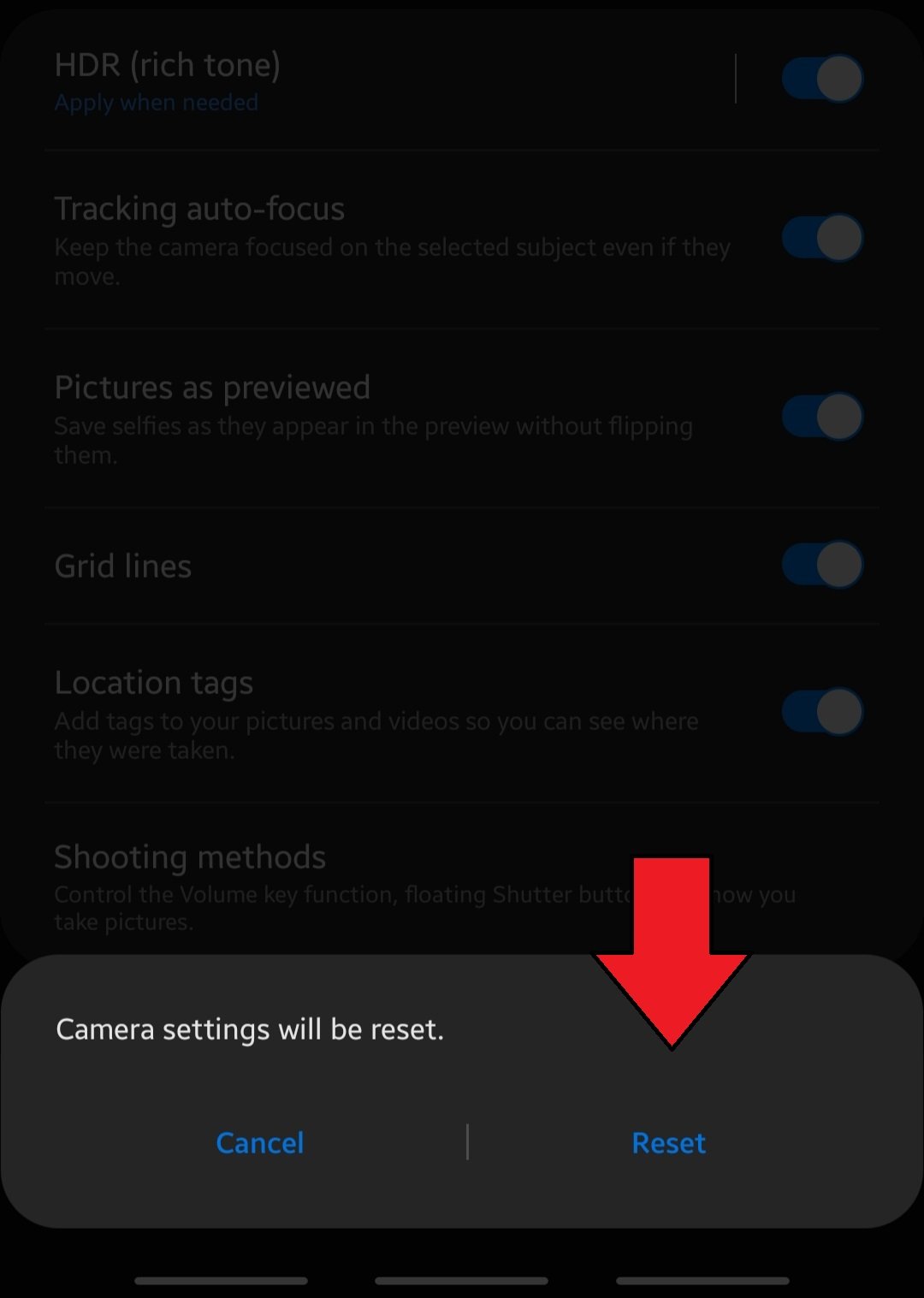 Fix random dark spots in photos by resetting camera settings.